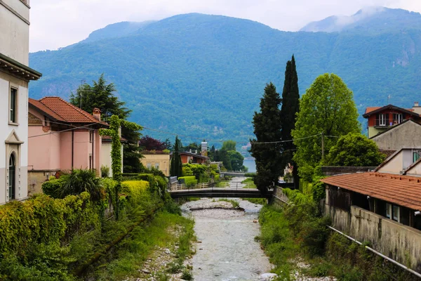 Güzel İtalyan kasabasında Mandello güzel evler, ağaçlar ve Alpler arka plan.