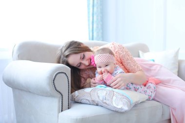 Çocuk ile kanepede oturan ve pembe elbise oldukça genç anne.