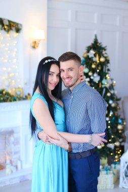 Elbise ayakta koca şömine ve Noel ağacı yakınındaki giyen beyaz kadın.