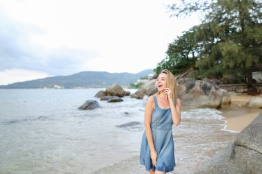 Genç Sarışın kadın yanında smartphone sabah deniz kıyısında söz.