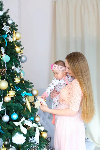 Pembe elbise giyen genç Avrupa ana holding kız silah ve ayakta yakınındaki hristmas ağaç,.