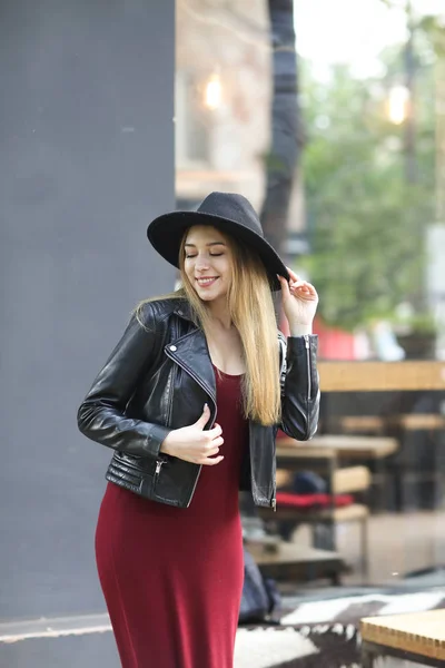 Young woman wearing black hat and red dress, and leather jacket.. — Stock Photo, Image