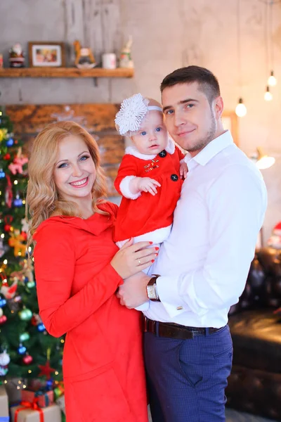 Noel ağacı yakınındaki kırmızı elbise giyen kadın ile ayakta genç adam.