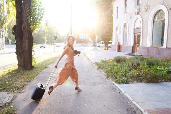 Giovane giornalista jocund indossa abito in piedi fuori con fotocamera e valise . — Foto Stock