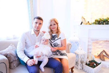 Genç baba ve kızı ile Divan dekore edilmiş şömine yakın oturan anne.