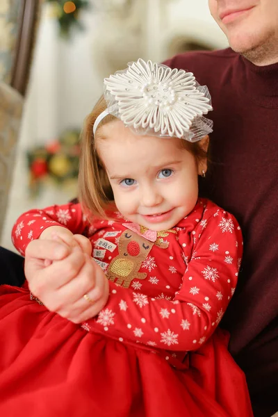 Pequena menina sorridente sentada com o pai e vestindo vestido vermelho . — Fotografia de Stock