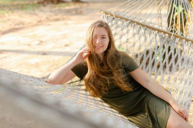 Beyaz hasır hamak yalan ve haki elbise genç güzel kadın.