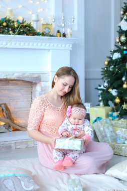 Küçük kızı dekore edilmiş şömine ve Noel ağacı mevcut hediye Genç beyaz anne.