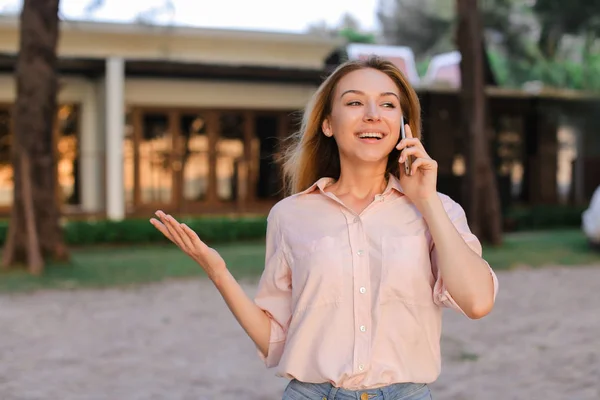 Joven mujer hablando por sartphone fuera, usando blusa . — Foto de Stock