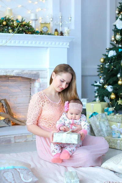 Küçük kızı dekore edilmiş şömine ve Noel ağacı mevcut hediye Genç beyaz anne.