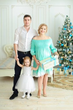 Küçük kızı Noel ağacı içinde arka plan mevcut, tutmak ile duran mutlu kadın.