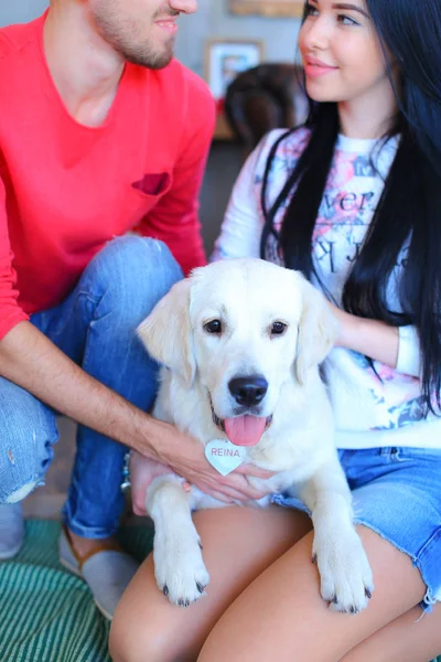 White labrador sitting on happy woman and man knees. — Stock Photo, Image