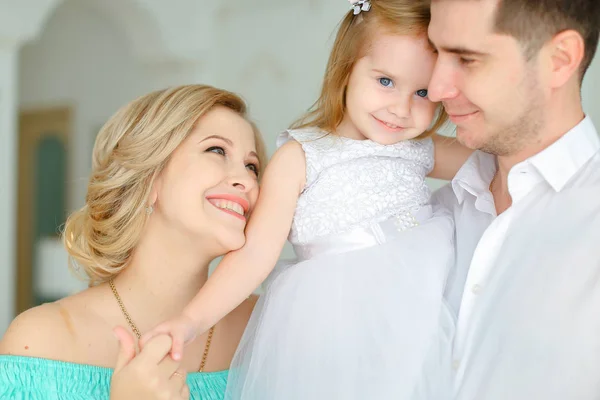 Caucasiano sorrindo pai mantendo pequena filha e jovem mãe beijando mão . — Fotografia de Stock