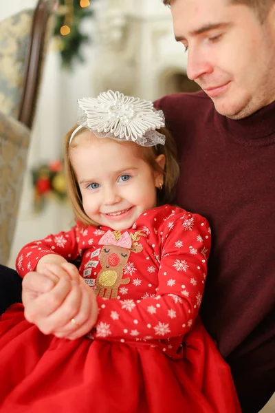 Pequena menina caucasiana sentada com o pai e vestindo vestido vermelho . — Fotografia de Stock