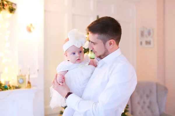 Joven padre besando pequeño bebé femenino y vistiendo camisa blanca . — Foto de Stock