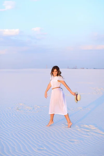 Молода біла жінка в білій сукні, що йде піском і тримається — стокове фото