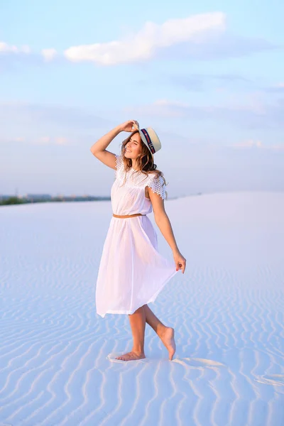 Молода жінка в білій сукні і капелюсі йде на пісок босо — стокове фото