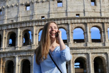 Genç kadın turist smartphone içinde Colosseum geçmiş Roma, İtalya tarafından konuşma.