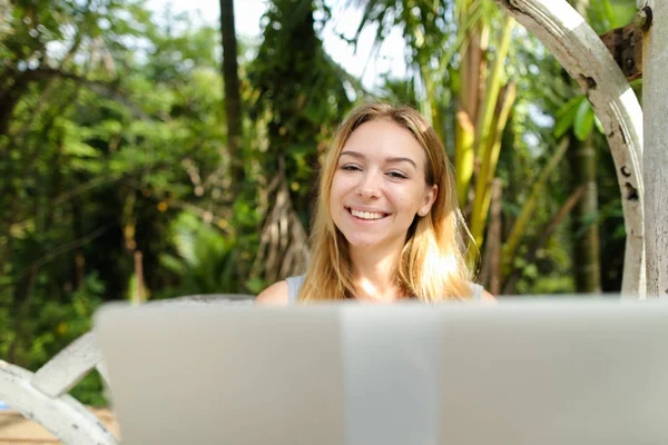 Young happy woman using laptop, palms in background. — Stock Photo, Image