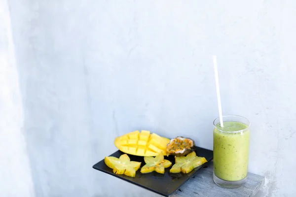 Mango und Karambola auf schwarzem Teller, Kiwigrün mit frischem Saft. — Stockfoto