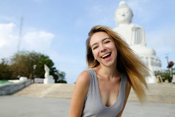 Portret van blond meisje permanent in de buurt van wit beton standbeeld van Boeddha in Phuket. — Stockfoto