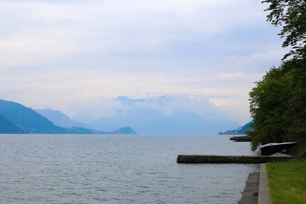 Vazio cais de concreto perto de barco no lago Como, Alpes montanhas no fundo . — Fotografia de Stock