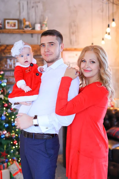 Junge kaukasische Frau und Mann stehen mit weiblichem Baby in der Nähe des Weihnachtsbaums. — Stockfoto