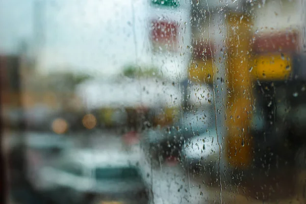 Σταγόνες βροχής σε γυαλί και αυτοκίνητα δρόμου στο παρασκήνιο, εστίαση σε νερό. — Φωτογραφία Αρχείου
