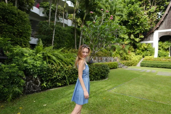 Jovem mulher de pé na grama verde perto da casa do resort . — Fotografia de Stock