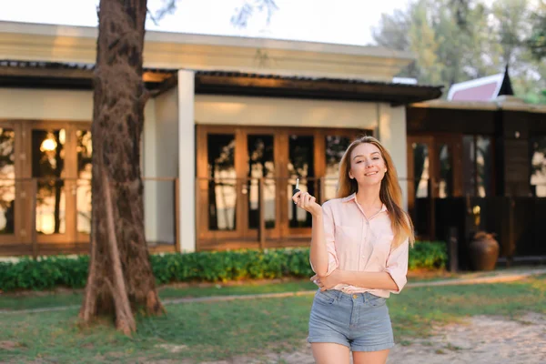 Menina de pé perto da casa do resort e mantendo as chaves . — Fotografia de Stock