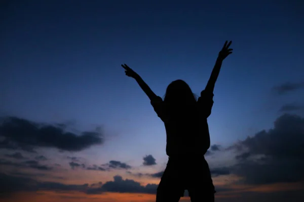 Silhouette de jeune femme au coucher du soleil ciel bleu foncé avec fond de nuages . — Photo