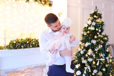 Noel ağacı yanında küçük kadın bebek tutmak ve şömine dekore edilmiş genç beyaz babası.