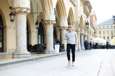 Yanında smartphone Binası arka planda sütunlarla yakınındaki konuşan genç adam.