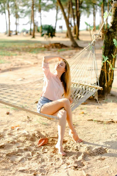 Jovem loira mulher pessoa sentada na rede de vime, fundo de areia . — Fotografia de Stock