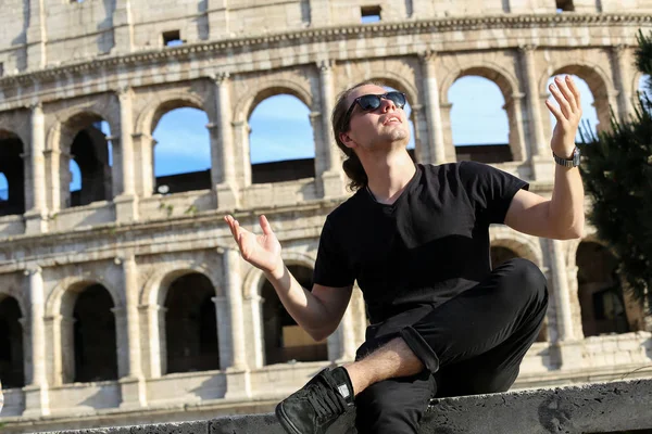 Młody mężczyzna turystycznych siedzi w pobliżu tło Koloseum w Rzymie. — Zdjęcie stockowe
