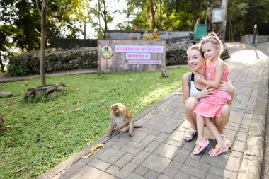 Tayland hayvanat bahçesindeki maymunlar yakın duran kızı ile genç gülümseyen anne.