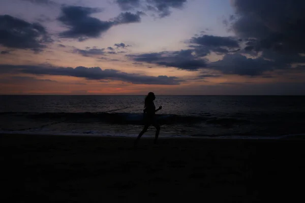 海と夕日を背景に女性のシルエットを実行. — ストック写真