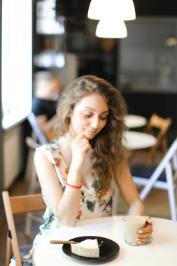 Kek ve kahve kafede oturan genç güzel kadın.