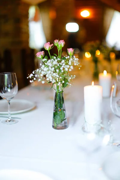 Ramo de flores y velas sobre mesa blanca . — Foto de Stock