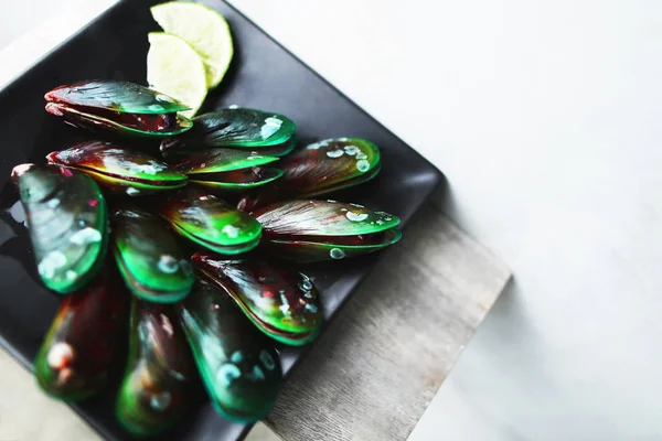 Tasty mussels on black square plate in white background. — Stock Photo, Image