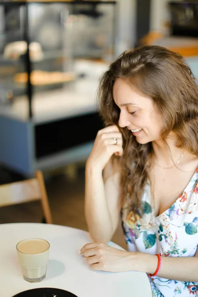 Młoda kobieta uśmiechający się filiżankę kawy siedząc w kawiarni i odpoczynku. — Zdjęcie stockowe
