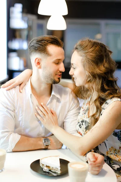 Junges Paar sitzt mit Kaffee, Kuchen und Umarmungen im Café. — Stockfoto