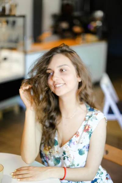 젊은 예쁜 여자 카페에 앉아 하 고 곱슬 머리를 만지고. — 스톡 사진