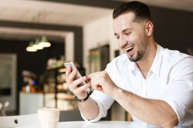 Kafede Smartphone kullanarak genç gülümseyen iş adamı.