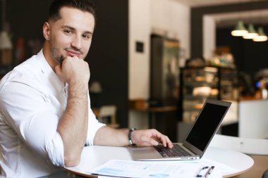 Genç başarılı işadamı belgeleri ve dizüstü bilgisayar ile café'de çalışma.