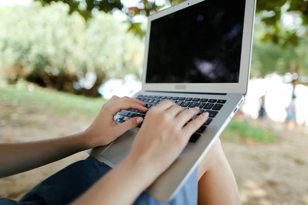 Mãos femininas brancas usando laptop com areia no fundo, tela preta . — Fotografia de Stock