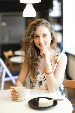Kek ve kahve kafede oturan genç kadın.