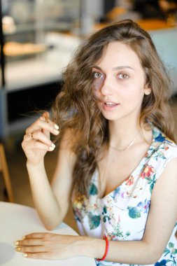 Kafede oturan ve kıvırcık saçlı dokunmadan Genç beyaz öğrenci.