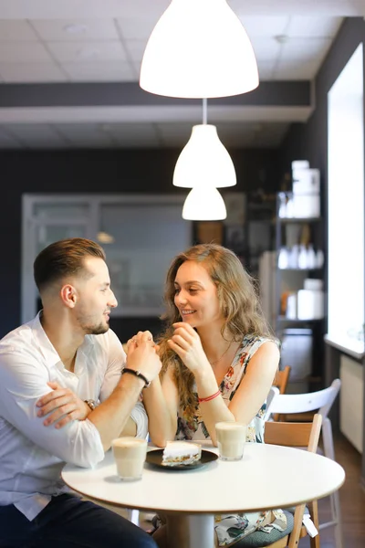 Junge schöne Mädchen und Jungen sitzen im Café in der Nähe von leckeren Kuchen und Händchen halten. — Stockfoto