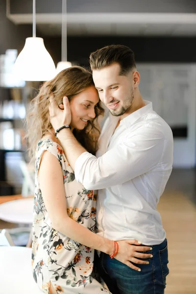 Joven chico caucásico vistiendo camisa blanca y abrazando a buena chica dentro . — Foto de Stock